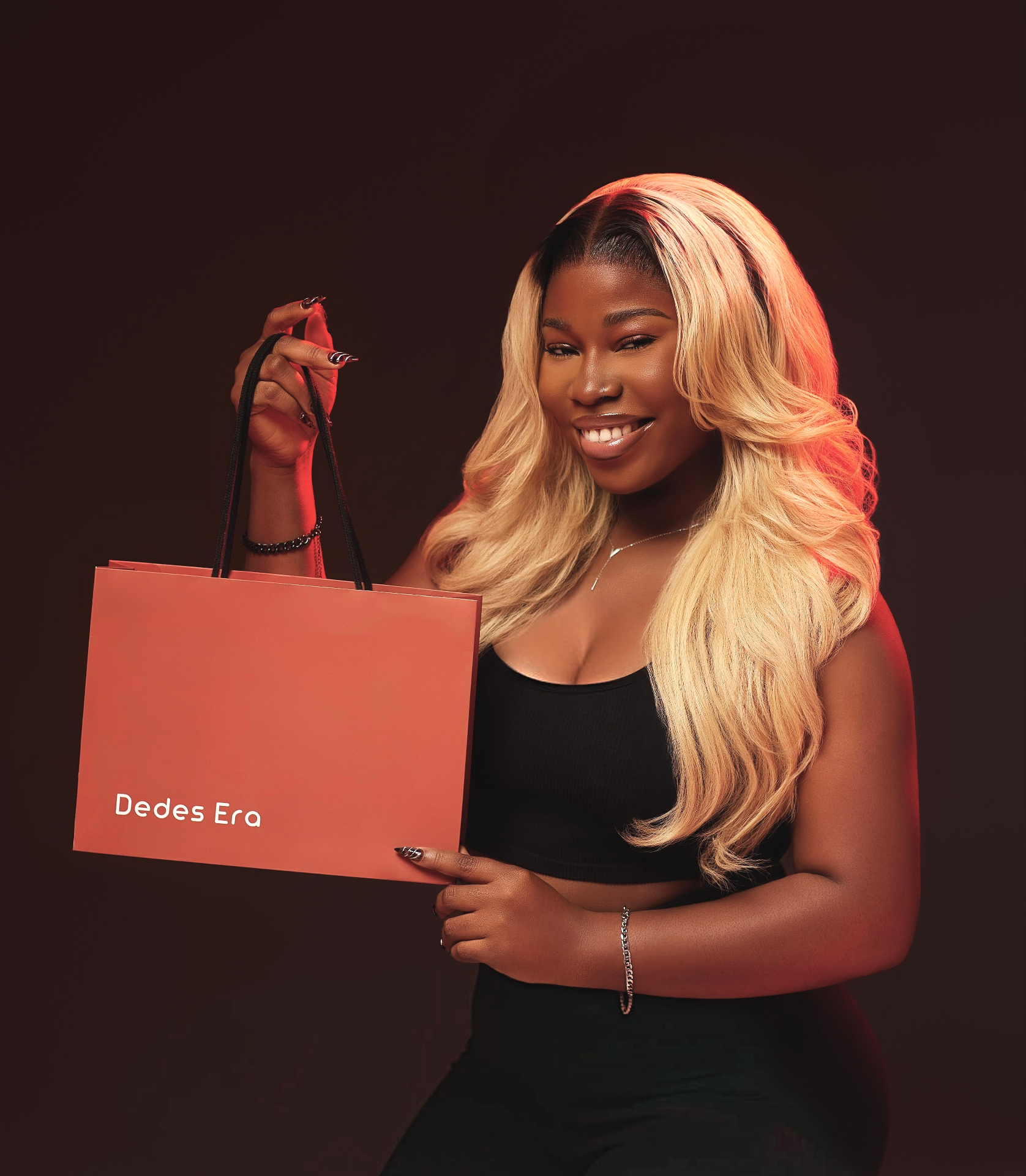 A woman holding the rust-coloured Dedes Era shopping bag — the flagship look of the brand